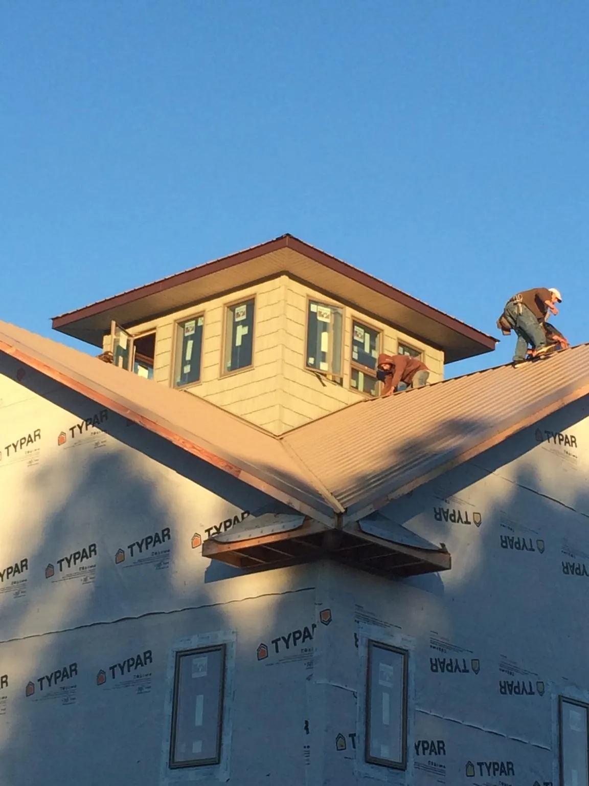 Roofers working around a rooftop cupola on a new metal roof at sunset — Roof Waterproofing in Athol by Roofing Brothers